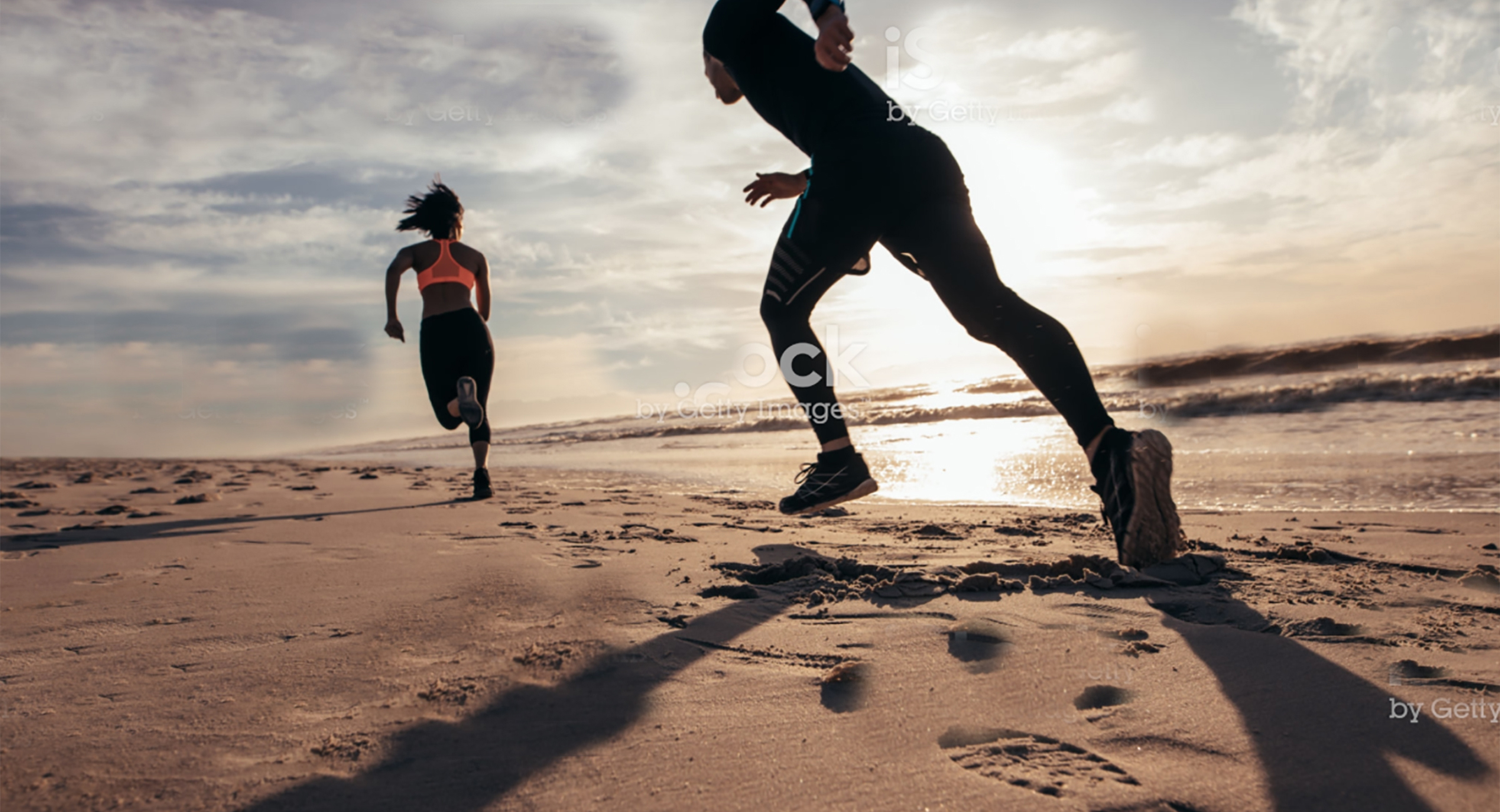 people running on a beach sunrise
